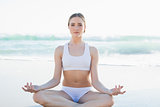 Gorgeous young woman meditating sitting on the beach
