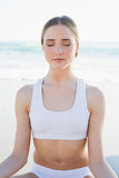 Young gorgeous woman sitting on the beach meditating