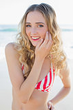 Cheerful young woman posing on the beach wearing a red bikini