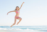 Attractive blonde woman jumping on the beach