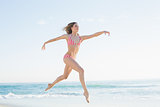 Pretty blonde woman jumping on the beach