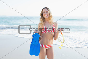 Joyful young woman holding flippers and a snorkel and diving goggles