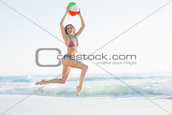 Cheerful young woman jumping on beach