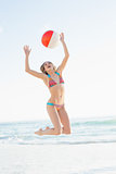 Joyful blonde woman throwing a beach ball
