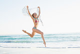 Happy slender woman jumping in the air holding shawl