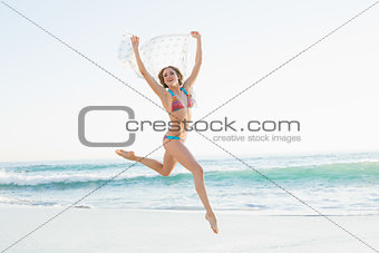 Euphoric slender woman jumping in the air holding shawl
