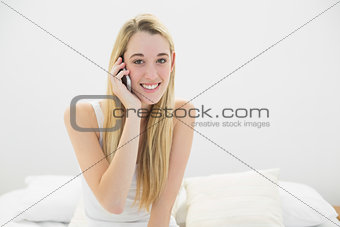 Attractive young woman phoning with her smartphone smiling at camera