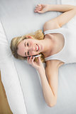 Content peaceful woman phoning with her smartphone while lying on her bed