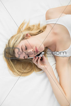 Chatting cute woman using her smartphone for phoning lying on her bed