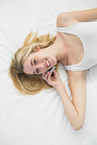 Gorgeous blonde woman phoning with her smartphone smiling at camera