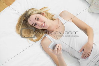 Lovely calm woman using her smartphone smiling at camera
