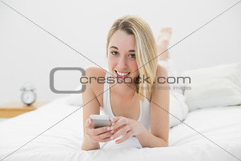 Beautiful relaxed woman holding her smartphone smiling at camera