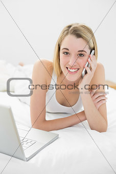 Beautiful blonde woman phoning peacefully lying on her bed