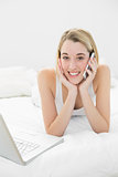 Attractive peaceful woman lying on her bed while phoning