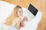 Gorgeous young woman lying on her bed using her notebook