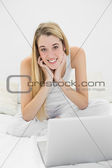 Content blonde woman smiling at camera while using her notebook