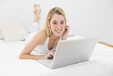 Beautiful woman lying on her bed using her laptop