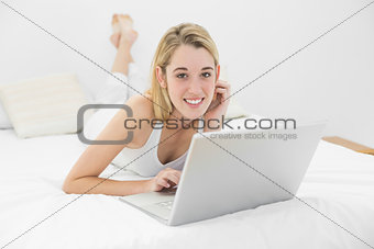 Beautiful woman lying on her bed using her laptop