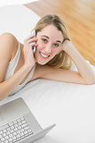 Cute woman phoning with her smartphone lying on her bed