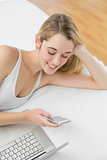 Pretty woman using her smartphone lying on her bed