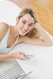 Gleeful blonde woman lying on her bed using her smartphone