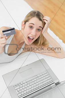 Successful surprised woman home shopping with her notebook looking at camera