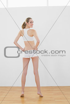 Rear view of beautiful slender woman posing in sports hall
