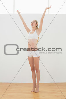 Gleeful fit woman in sportswear stretching raising her arms