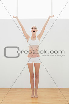 Cute toned woman raising her arms for stretching her body
