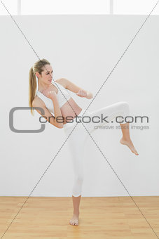 Focused fit woman wearing sportswear doing martial arts