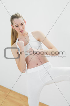 Concentrated young woman in sportswear doing martial arts