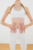 Mid section of slender blonde woman touching her belly