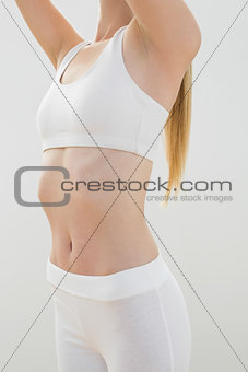 Slender young woman wearing sportswear posing raising her arms