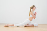 Calm ponytailed woman doing yoga pose sitting on floor