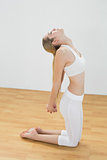 Cute fit woman stretching her body kneeling on floor