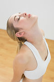 Lovely sporty woman stretching kneeling on floor in sports hall