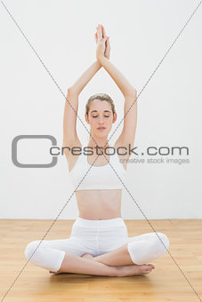 Attractive calm woman practising yoga sitting in lotus position in sports hall