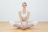 Beautiful woman sitting in lotus position on floor in sports hall