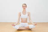 Cute slim woman meditating sitting in lotus position in sports hall