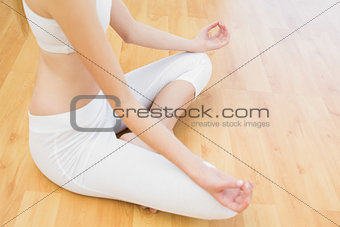 Young slender woman sitting on floor in lotus position