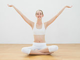 Cheerful calm woman sitting in lotus position in sports hall