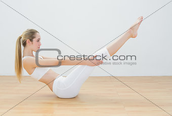 Sporty young woman doing sports exercise sitting on floor