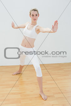 Focused fit woman practising yoga standing in sports hall