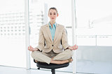 Lovely chic businesswoman sitting in lotus position on her swivel chair