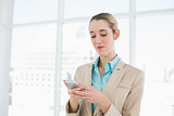 Concentrated chic businesswoman texting with her smartphone