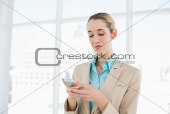 Concentrated chic businesswoman texting with her smartphone