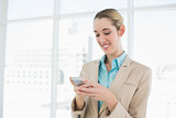 Attractive ponytailed businesswoman texting with her smartphone