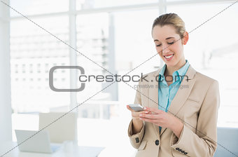 Content classy businesswoman texting with her smartphone
