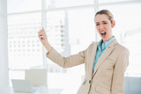 Cute shocked businesswoman holding her smartphone looking at camera