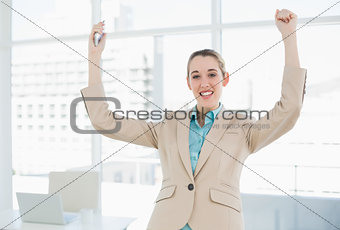 Chic businesswoman cheering standing in her office